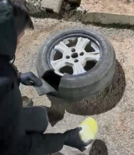 Bir polis memuru bir aracın lastiğini kontrol ediyor.-1