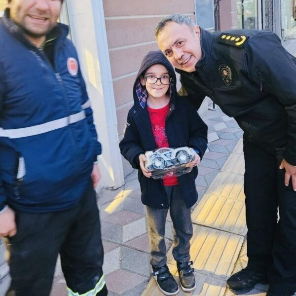 Çocuk polis arabası hediye alıp sevinçle gülümsüyor.