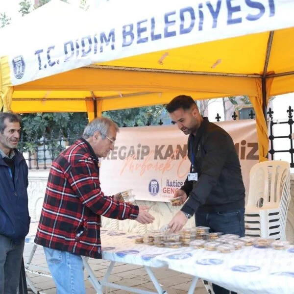 Didim Merkez Camii önünde kurulan stantta vatandaşlar kandil simidi yiyor.-2